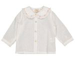 The Kidiwi Baby Girls' Lorena Blouse is an off-white plumetis long-sleeved shirt with a pink-trimmed Peter Pan collar, delicate ruffles, and front button closure.