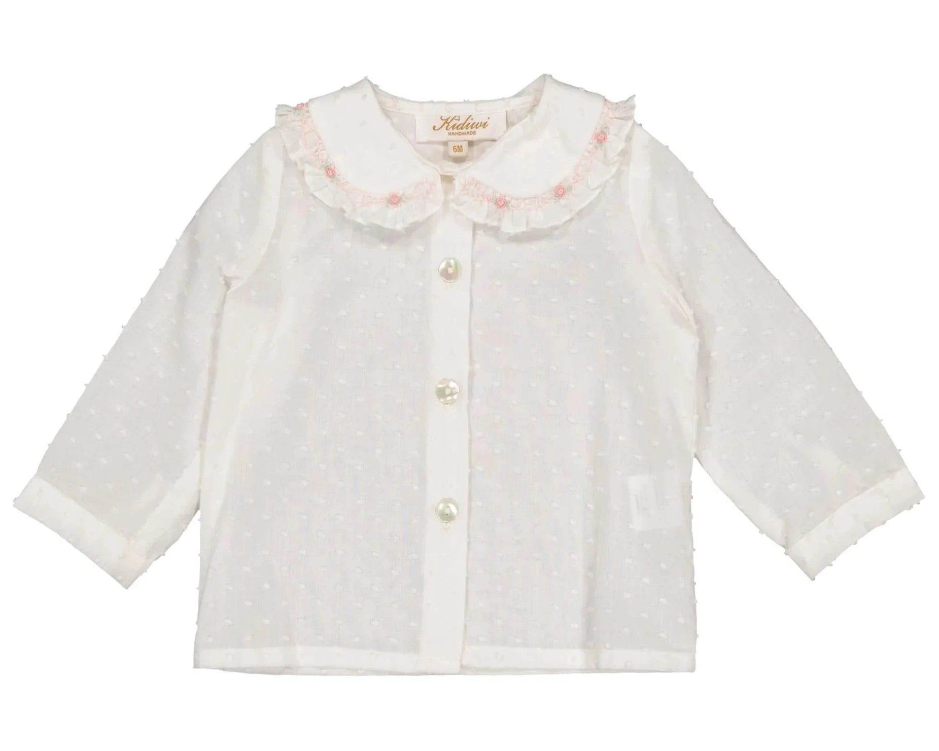 The Kidiwi Baby Girls' Lorena Blouse is an off-white plumetis long-sleeved shirt with a pink-trimmed Peter Pan collar, delicate ruffles, and front button closure.
