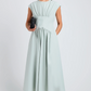 A woman in the Nyssa Dress by Proenza Schouler White Label—a light blue, sleeveless A-line piece with delicate shirring—holds a black clutch against a plain background.