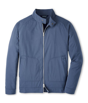 The Discovery Bomber Jacket by Peter Millar is a blue, zip-up jacket made from lightweight Italian twill, featuring a stand collar and two front pockets, shown on a white background.