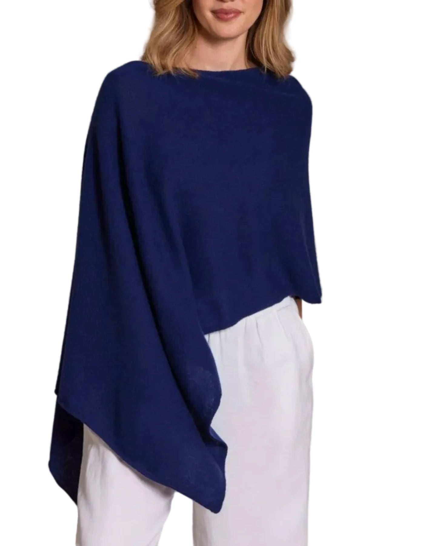 A woman stands against a white background, wearing the Alashan Cashmere Cashmere Dress Topper Poncho in loose navy blue layered over white pants—a versatile choice for effortless day-to-night style.