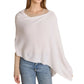 A woman wearing a beige sweater, light blue jeans, and the Alashan Cashmere Dress Topper Poncho in white stands against a white background, effortlessly exemplifying the versatile elegance of this staple piece—perfect for transitioning seamlessly from day to night.