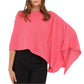 A woman exudes effortless style in the vibrant pink Cashmere Dress Topper Poncho by Alashan Cashmere, the ideal wardrobe essential for a seamless day-to-night transition, elegantly draped over black pants.