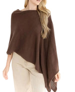 A woman stands against a white background wearing the Alashan Cashmere Cashmere Dress Topper Poncho in brown, styled effortlessly with light beige pants—a versatile look ideal for transitioning seamlessly from day to night.