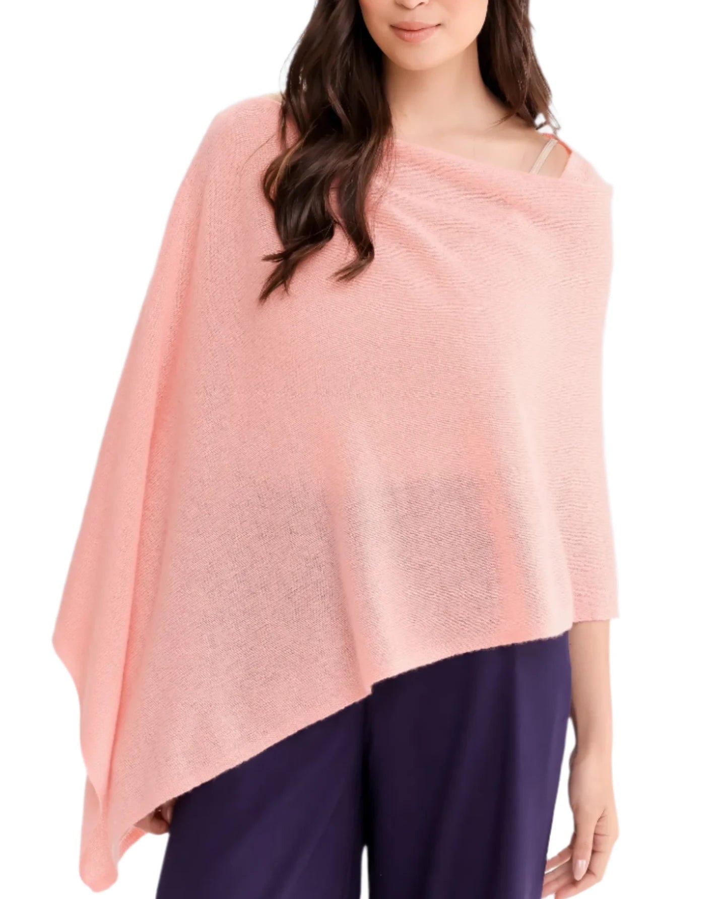 A person is wearing the Alashan Cashmere Cashmere Dress Topper Poncho in light pink paired with dark pants, creating a look that easily transitions from day to night. This effortlessly chic ensemble stands out against a white background, making it a true wardrobe essential.