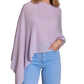 A woman is wearing the Alashan Cashmere Cashmere Dress Topper Poncho in light purple paired with light blue jeans, her hand in her pocket, set against a white background. This versatile poncho is a true wardrobe essential, effortlessly transitioning from day to night.