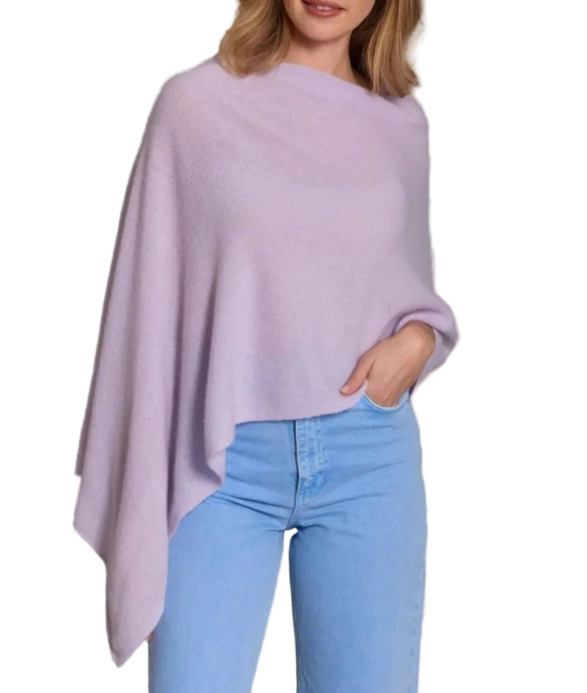 A woman is wearing the Alashan Cashmere Cashmere Dress Topper Poncho in light purple paired with light blue jeans, her hand in her pocket, set against a white background. This versatile poncho is a true wardrobe essential, effortlessly transitioning from day to night.