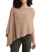 A woman wears the Alashan Cashmere Cashmere Dress Topper Poncho in beige, paired with olive green cargo pants, standing against a plain white background—a versatile wardrobe staple ideal for effortless day-to-night transitions.