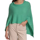 A person wears the Alashan Cashmere Cashmere Dress Topper Poncho—a relaxed, green poncho-style top—paired effortlessly with beige pants, standing against a white background.