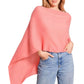 A woman stands against a white background with one hand in her pocket, wearing the Alashan Cashmere Cashmere Dress Topper Poncho in light pink over blue jeans. This versatile piece is a true wardrobe essential, effortlessly elevating your look from day to night.