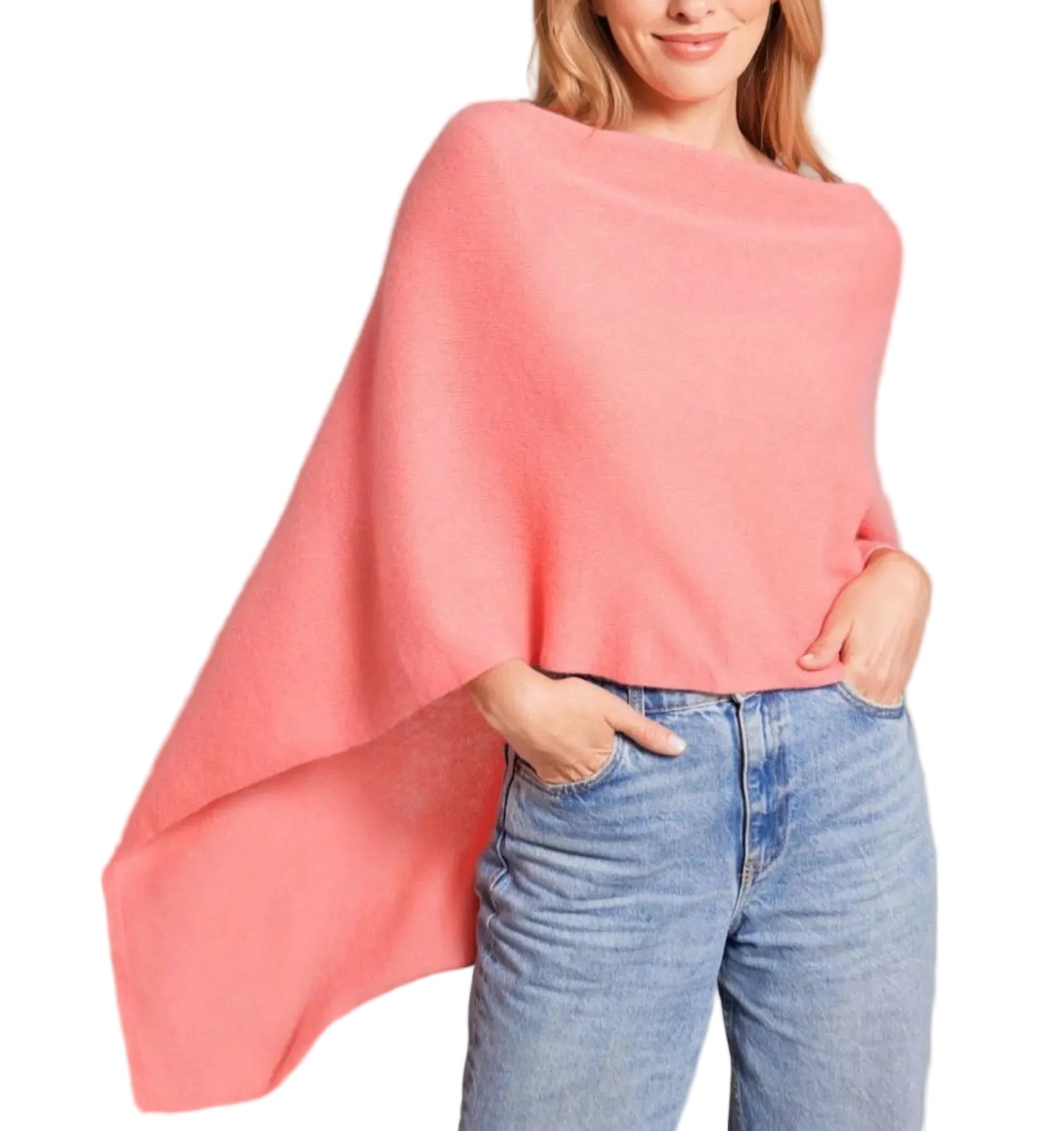 A woman stands against a white background with one hand in her pocket, wearing the Alashan Cashmere Cashmere Dress Topper Poncho in light pink over blue jeans. This versatile piece is a true wardrobe essential, effortlessly elevating your look from day to night.