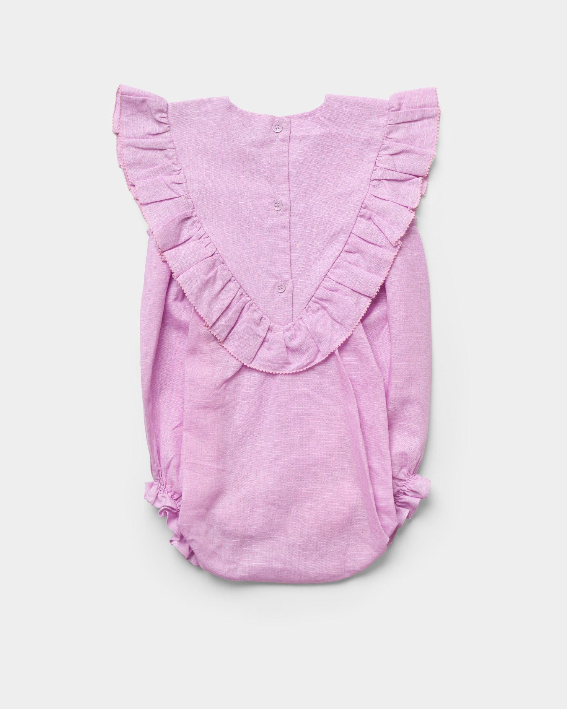The Early Sunday Baby Girls’ Lucy Baby Bubble Romper, shown flat on a white background, features a light pink cotton-linen blend with ruffled detailing along the shoulders and a button-up back.