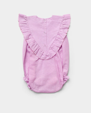 The Early Sunday Baby Girls’ Lucy Baby Bubble Romper, shown flat on a white background, features a light pink cotton-linen blend with ruffled detailing along the shoulders and a button-up back.