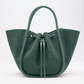 The Proenza Schouler Small Ruched Soft Suede Tote in green features structured handles, a sculptural silhouette, and a drawstring closure, showcased on a plain white background.