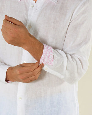 A person adjusts the cuff of a Pink House Mustique Mens' Solid Linen Shirt, revealing its pink patterned inner lining and highlighting the shirt's stylish comfort and breathable linen fabric.
