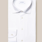Folded Four-Way Stretch Shirt, Slim Fit by Eton, set against a beige background. Known for its tech fabric offering exceptional comfort, the white shirt comes with a corner tag reading "More Sustainable.