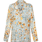 The Silice Shirt by Agua By Aguabendita is a chic, long-sleeve top with a yellow and blue floral print on white—perfect for adding versatile style to any wardrobe.