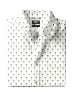 A Faherty Movement Shirt, white Supima cotton with short sleeves and an all-over small palm tree print, is neatly folded with the "Faherty" brand label visible on the collar.