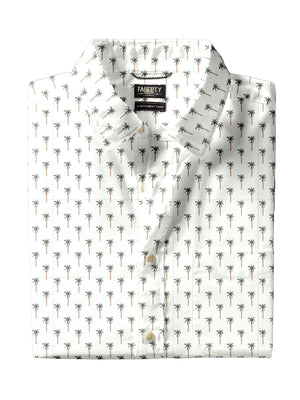 A Faherty Movement Shirt, white Supima cotton with short sleeves and an all-over small palm tree print, is neatly folded with the "Faherty" brand label visible on the collar.