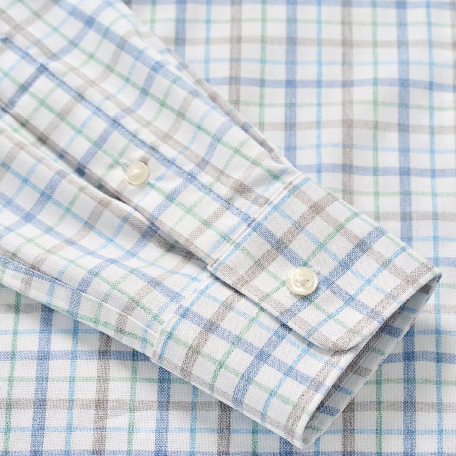 Close-up of the Johnnie-O Maarten Button Down, a wrinkle-resistant shirt with a white base and blue, green, and brown plaid pattern, featuring a buttoned cuff.