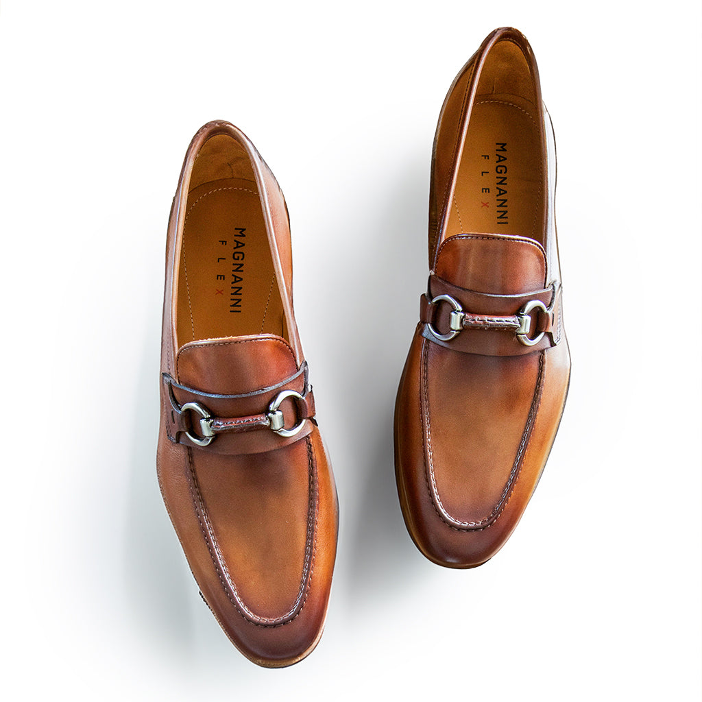 Magnanni's Diago Loafers, crafted from brown calfskin leather and featuring a metal bit detail, are labeled "Línea Flex" and photographed from above on a white background.