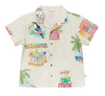 The Boys' Magnum Shirt by Arsene & Les Pipelettes is a short-sleeve, button-up cotton shirt featuring vibrant prints of toucans, palm trees, fruit stands, and playful "HAY" and "COCOS" signs on a light background. It’s designed in a relaxed fit to keep boys comfortable all day long.