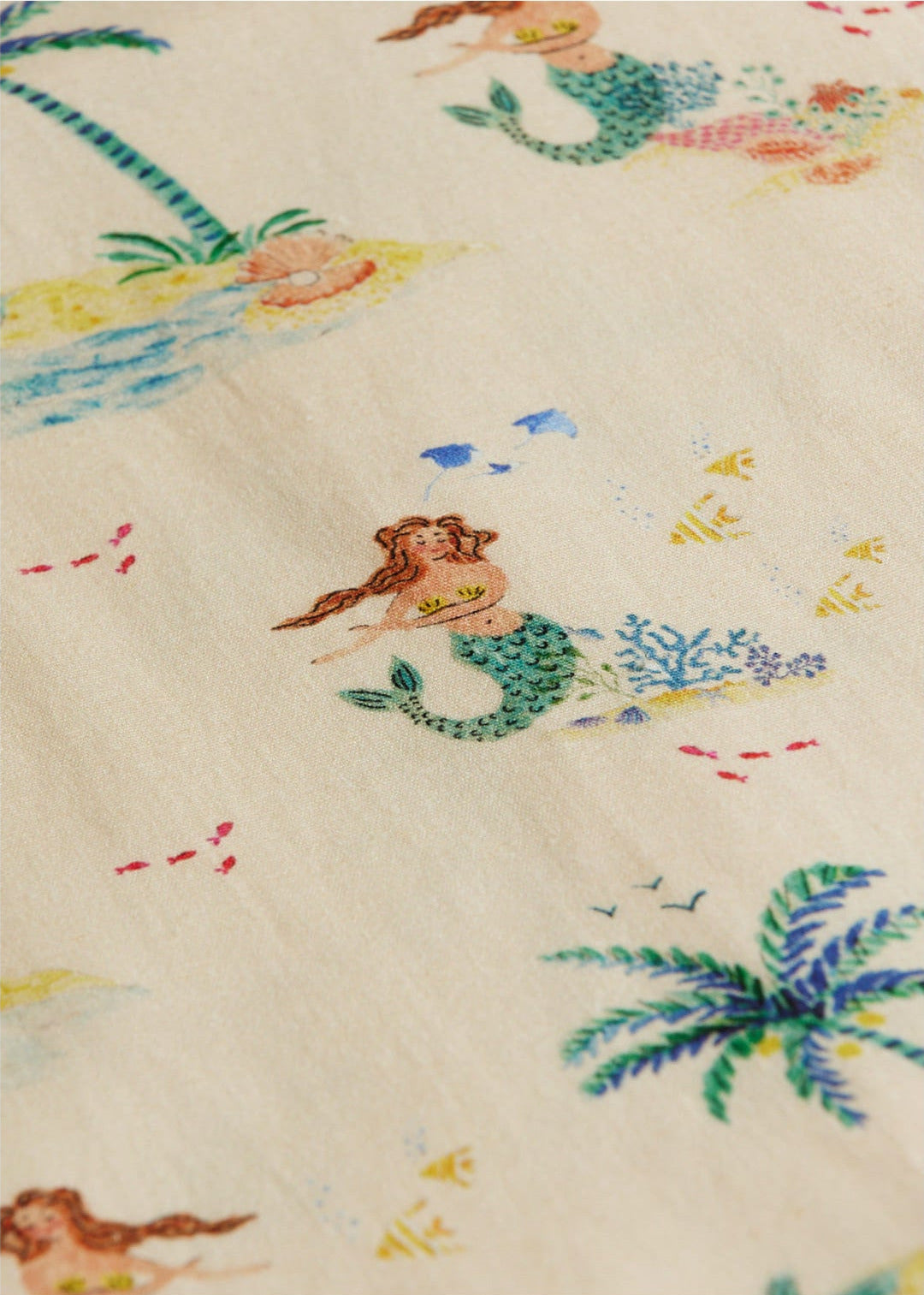 The Kids' Federico Shirt by Arsene & Les Pipelettes features a whimsical cream fabric with green-tailed mermaids, fish, coral, palm trees, and sandy islands—ideal for making a fun statement.