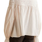 The back view of a woman wearing a white Merlette New York Merlette Majorelle Top with ruffles.