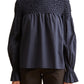 The model is wearing a Merlette New York Merlette Majorelle Top with ruffled sleeves.