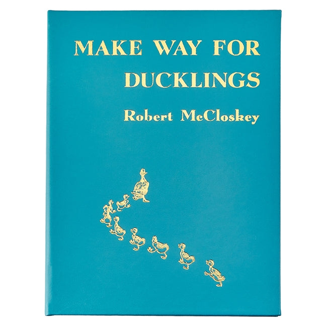 Cover of Graphic Image's "Make Way For Ducklings, Leather" by Robert McCloskey, featuring gold illustrations of Mallards leading ducklings on a teal background that bring the illustrated tale to life.