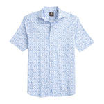 The Johnnie-O Filipe Shirt is a coastal-inspired short-sleeve button-up featuring a light blue floral pattern on a white background, complete with a smart button-down collar and shown laid flat on a white surface.