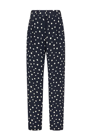 The Mariquita Nana Pants by Blaze Milano are navy blue silk, high-waisted trousers with white polka dots, a straight-leg cut, and elegant pleats at the waistband.