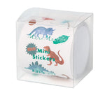 A clear box holds a roll of Meri Meri Themed Stickers—dinosaur mini stickers labeled "Mini Stickers" and "Autocollants" in green, ideal as a fun gift or for party prizes.