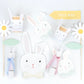 Meri Meri's Easter Bunny Plates feature paper craft bunny faces with bow ties and rabbit ears, including a charming lop-eared bunny, surrounded by daisy and arrow cutouts on a white background—perfect for an Easter party display!.