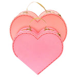 The Meri Meri Heart Suitcase, Large, in light pink and peach with gold glittery handles and edge stitching, overlap each other. An ideal Valentine's Day gift from Meri Meri, these charming accessories add a romantic touch.