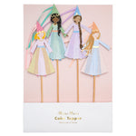 The Meri Meri Cake Toppers set includes four stick cake toppers, each featuring paper cutouts of princesses adorned in various pastel-colored dresses and cone hats. The packaging is labeled "Meri Meri Princess Cake Topper.