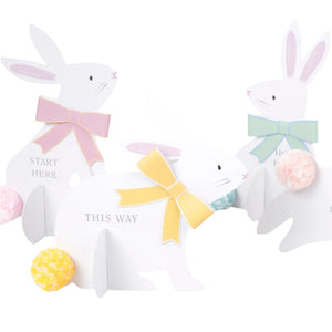 The Meri Meri Egg Hunt Kit includes three stylish bunny signs with pastel bows and pom-pom tails, featuring directional cues like "Start Here" and "This Way," perfect for adding a festive touch to your Easter celebration.