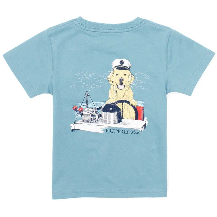 The Boys' Short-Sleeve Tee by Properly Tied showcases hand-drawn graphics of a dog in a captain's hat, lounging on a boat with lobsters and buoys. This blue Pima cotton shirt features "Properly Tied" text, combining style and comfort effortlessly.