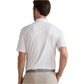 A man is seen from behind in a white Peter Millar Featherweight Mélange Polo tucked into light beige pants with a gray belt, providing performance fabric comfort and UPF 50+ sun protection.