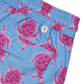 Close-up of the Turtle Trunks from Pink House Mustique, showcasing blue swim shorts with a playful pink sea turtle pattern and an elastic waistband. Designed with a buttoned pocket and crafted from quick-dry recycled fabric, these stylish swim trunks combine comfort and sustainability for your days by the water.