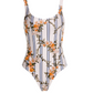 The Gema One Piece by Agua By Agua Bendita features a white base with black vertical stripes, an orange floral print, and UPF 50 sun protection—combining chic style with safety.