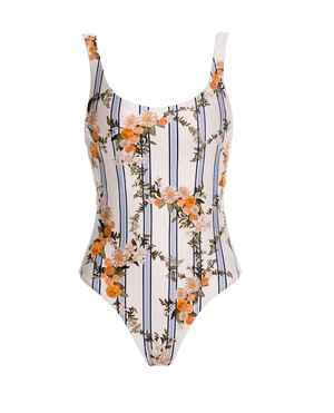 The Gema One Piece by Agua By Agua Bendita features a white base with black vertical stripes, an orange floral print, and UPF 50 sun protection—combining chic style with safety.