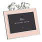 The Michael Aram Elephant Frame 4X6 - Pink features a pink border with silver trim and three silver elephants on top—perfect for displaying cherished memories in style. The center displays “Michael Aram” and “4x6.”.