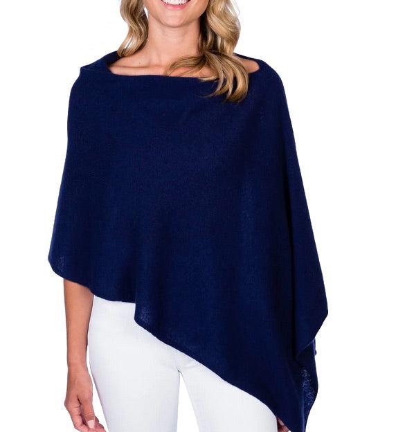 A woman wearing a navy Alashan Cashmere cashmere dress topper poncho for a versatile day-to-night wardrobe.