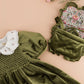 Green olive velvet dress with puffed sleeves, white embroidered collar, Kidiwi’s Mimosa Smocked Shoulder Bag, floral patterned item, and pink carnation on beige—featured in the winter 2025 collection.