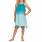 A young child models the Mer Girls’ Mini Chantal Dress, a sleeveless blue ombre summer dress featuring tassels at the hem, while standing barefoot against a plain white background.
