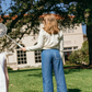 A girl wearing Minnow’s Girls' Chambray Embroidered Paperbag Pant stands on grass with a badminton racket, facing away from the camera; trees and a building appear in the background.