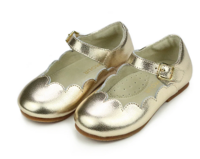 The Girls' Sonia Scalloped Flat by L'Amour Shoes features gold metallic finish, scalloped trim, ankle straps, and small buckles—an essential flat for girls shown on a white background.