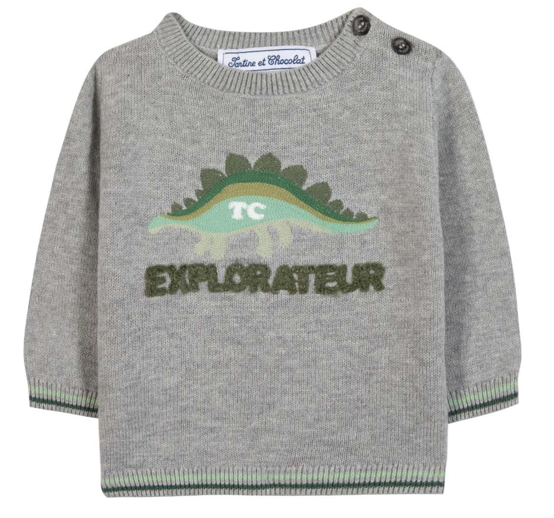 The Tartine et Chocolat Baby Boys’ and Toddler Knitted Sweater is crafted from 100% cotton in gray and features a playful green dinosaur graphic with the phrase “TC EXPLORATEUR” on the front, two buttons on the left shoulder, and green trim on the cuffs and hem.