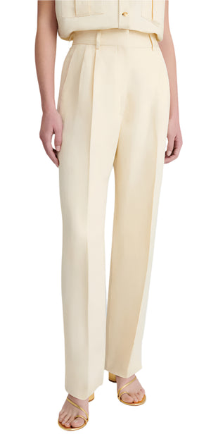 Person wearing Blaze Milano's BZM Savannah Fox Pants, featuring light beige high-rise wide-leg trousers with pleats, paired with a matching sleeveless top made from a luxurious linen-silk blend, and gold heeled sandals.